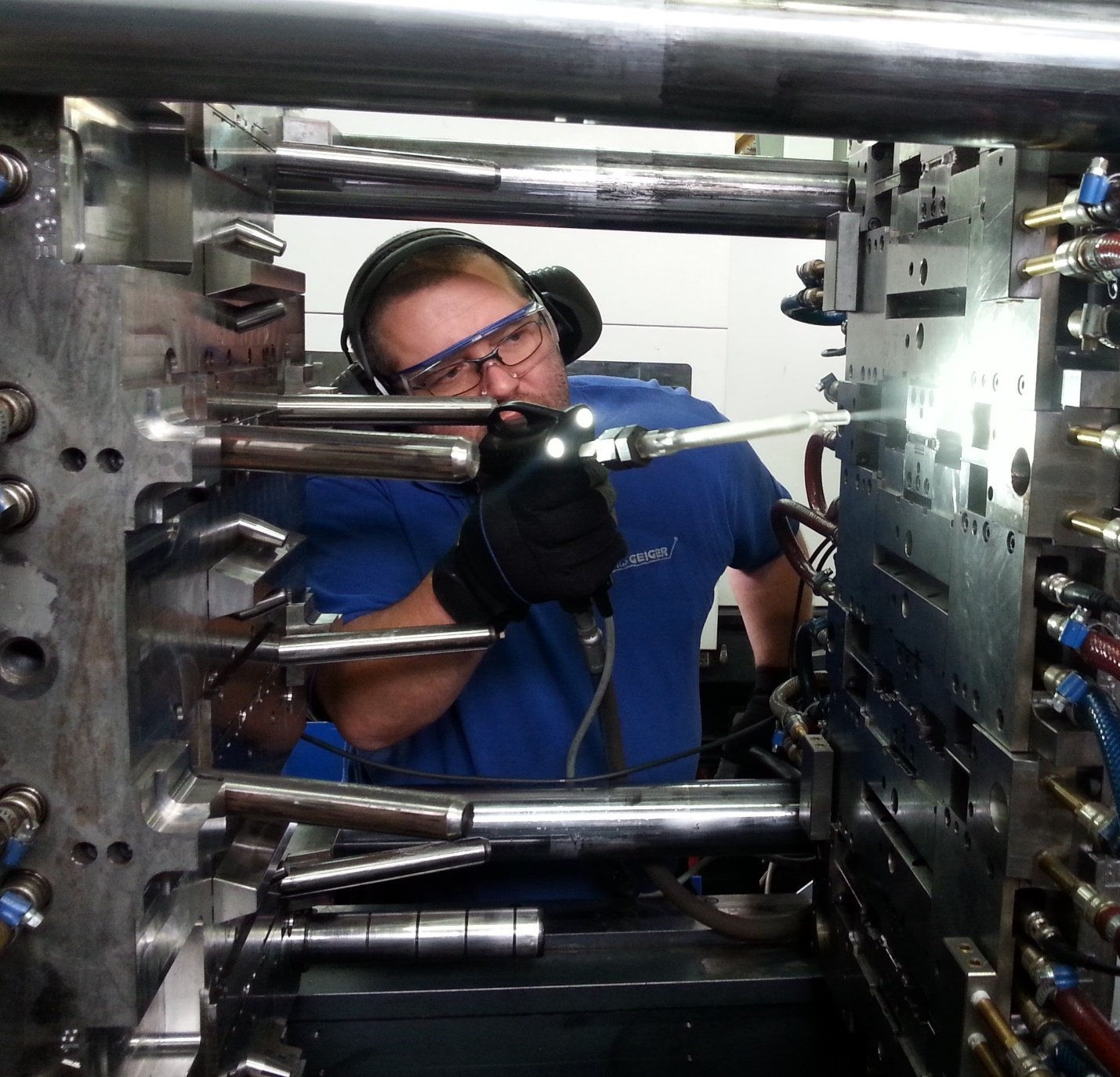 Técnico limpiando un molde de inyección de plástico con una boquilla de proyección de hielo seco.